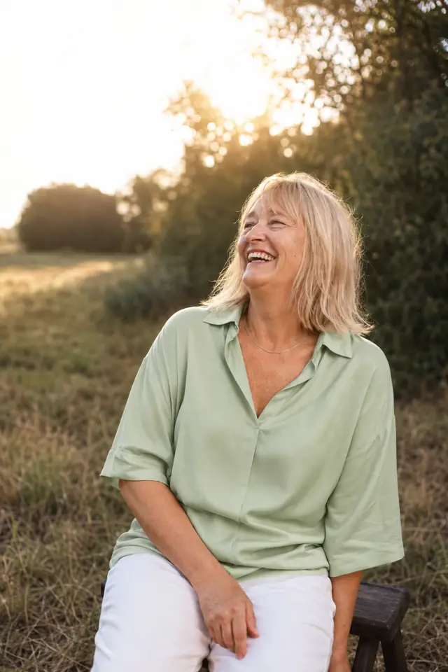 After: the same woman in a relaxed brand photo, sitting in a field at golden hour