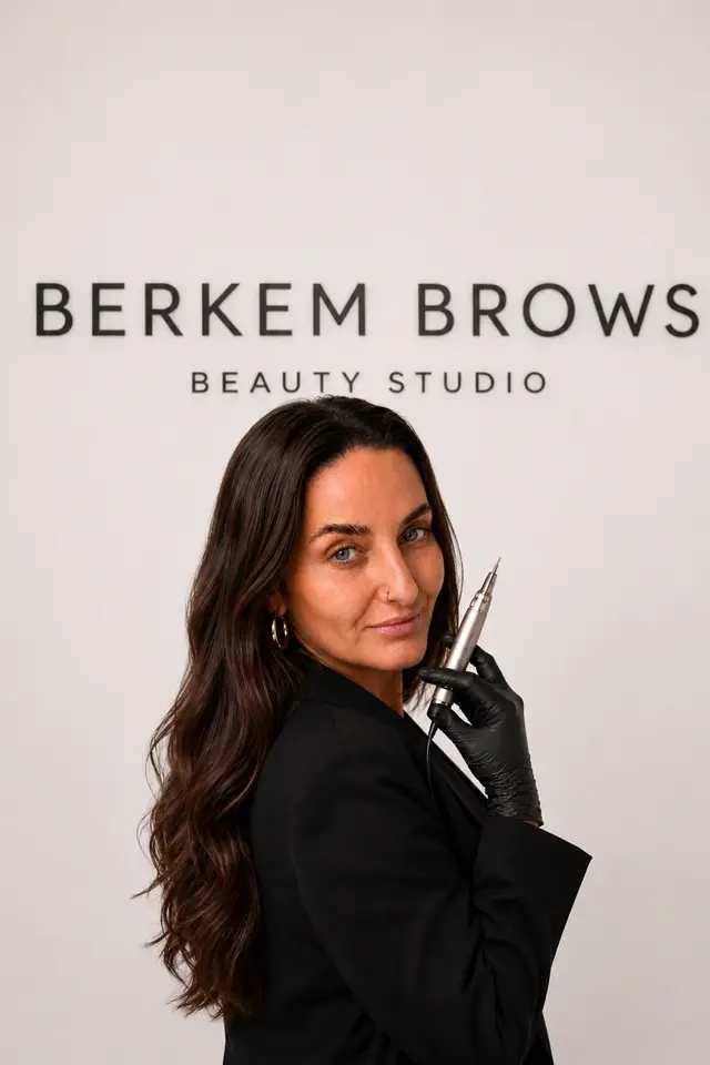Kellen holding a brow pen in front of the Berkem Brows logo